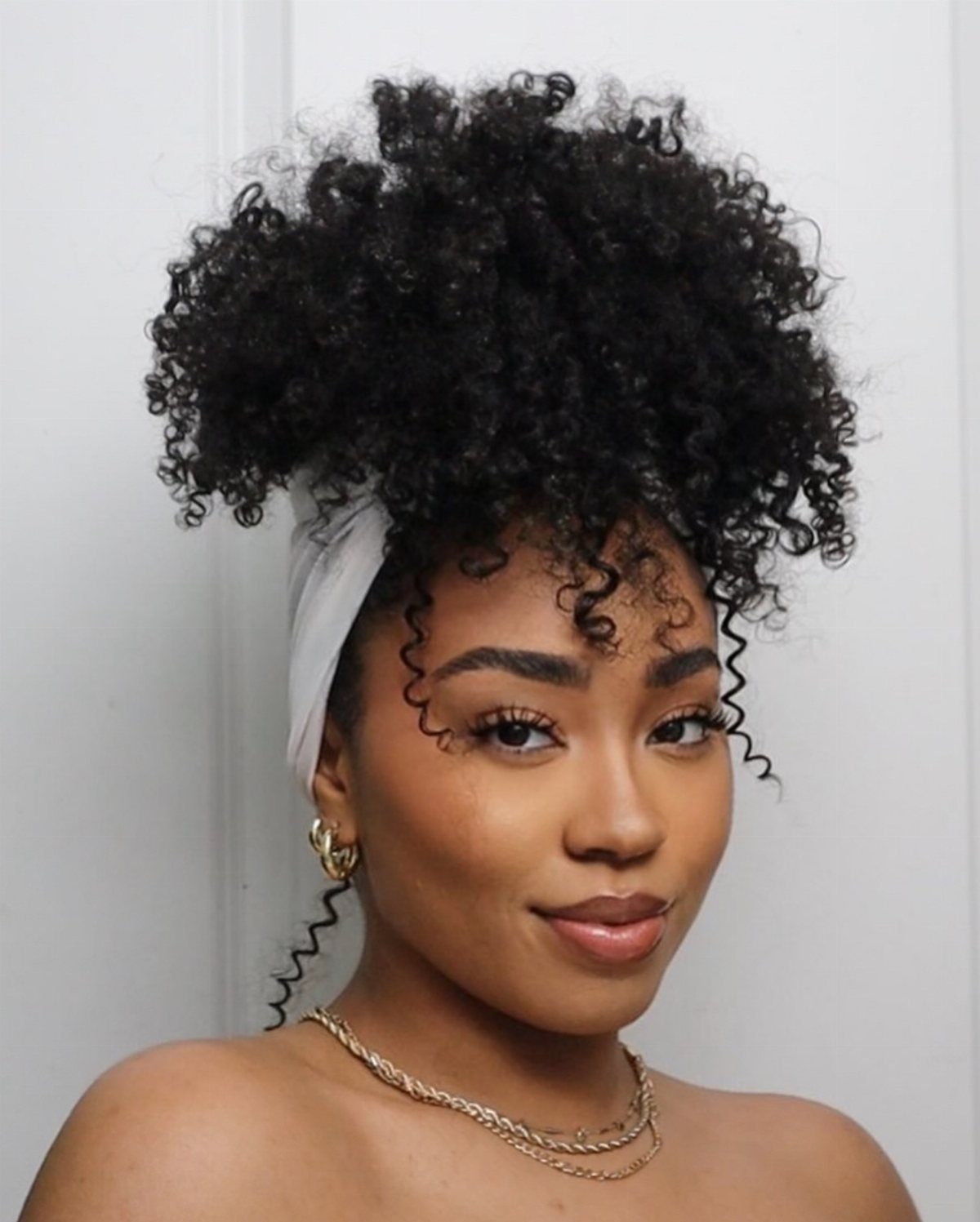 Woman with voluminous dark 3a curls styled in a high puff