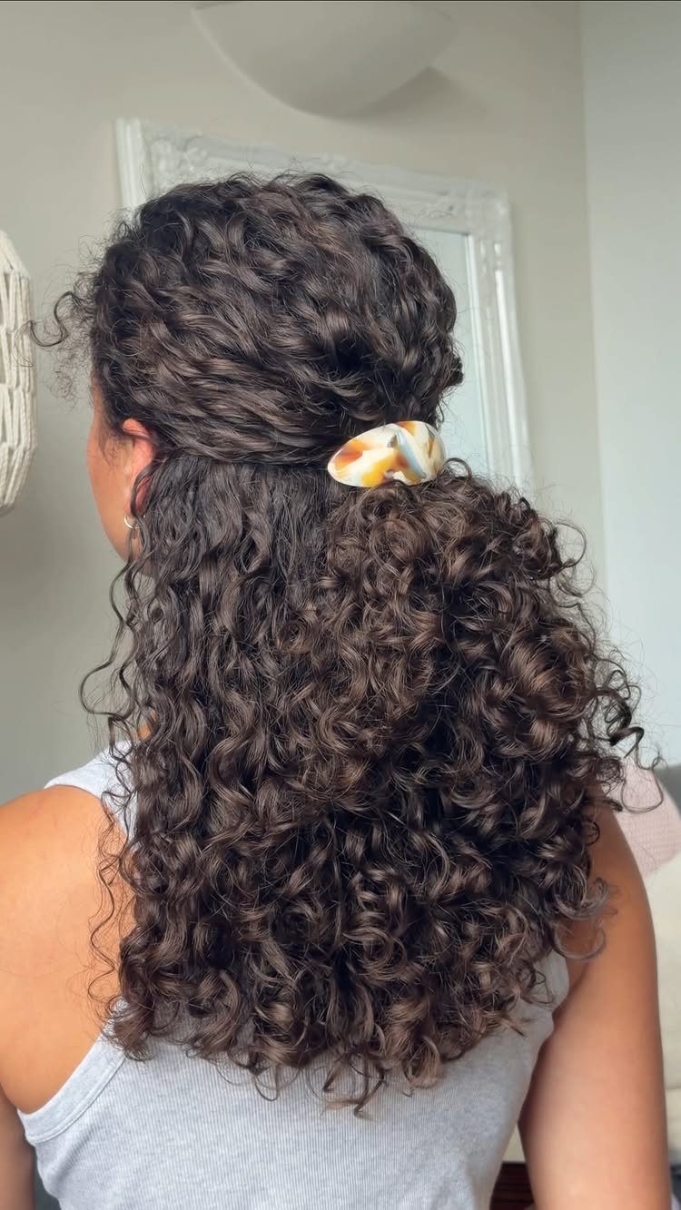 Long dark brown curls gathered half-up with a colorful clip