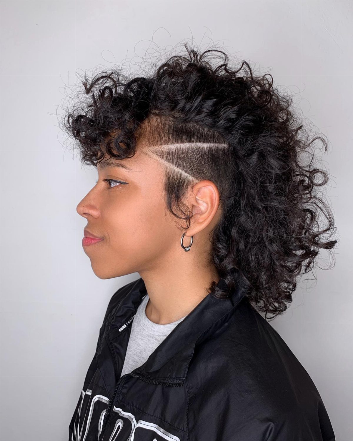 Woman showing voluminous curls with a shaved, line-patterned undercut