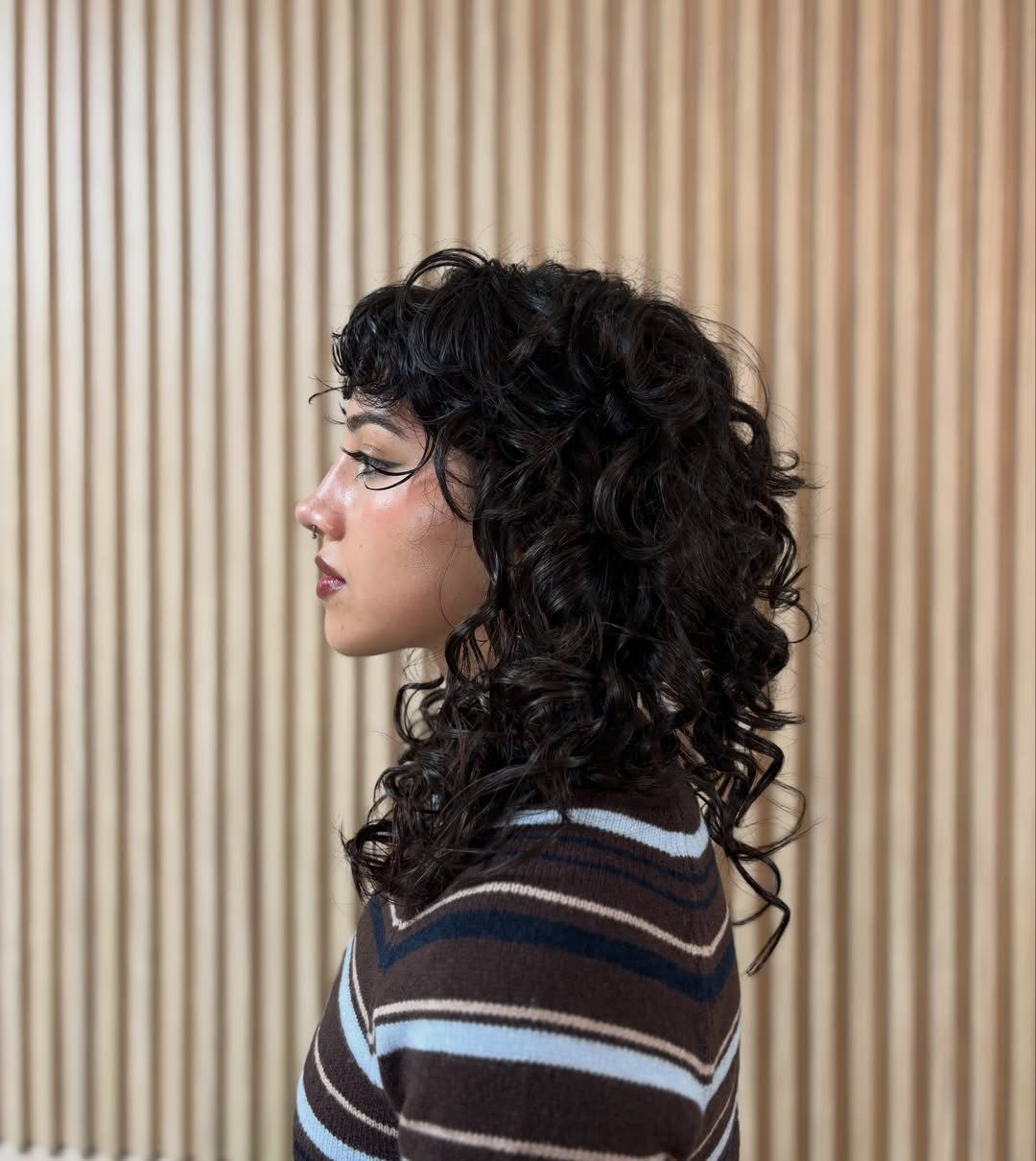 Dark curly shag with short bangs and layered, tapered shoulder-length curls