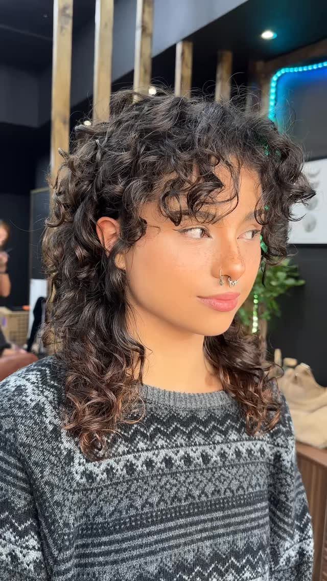 Person showing curly shoulder-length hair with wispy bottleneck bangs