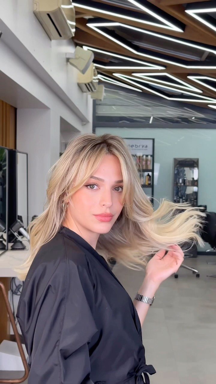 Blonde woman showing long beachy waves and wispy curtain bangs in a salon