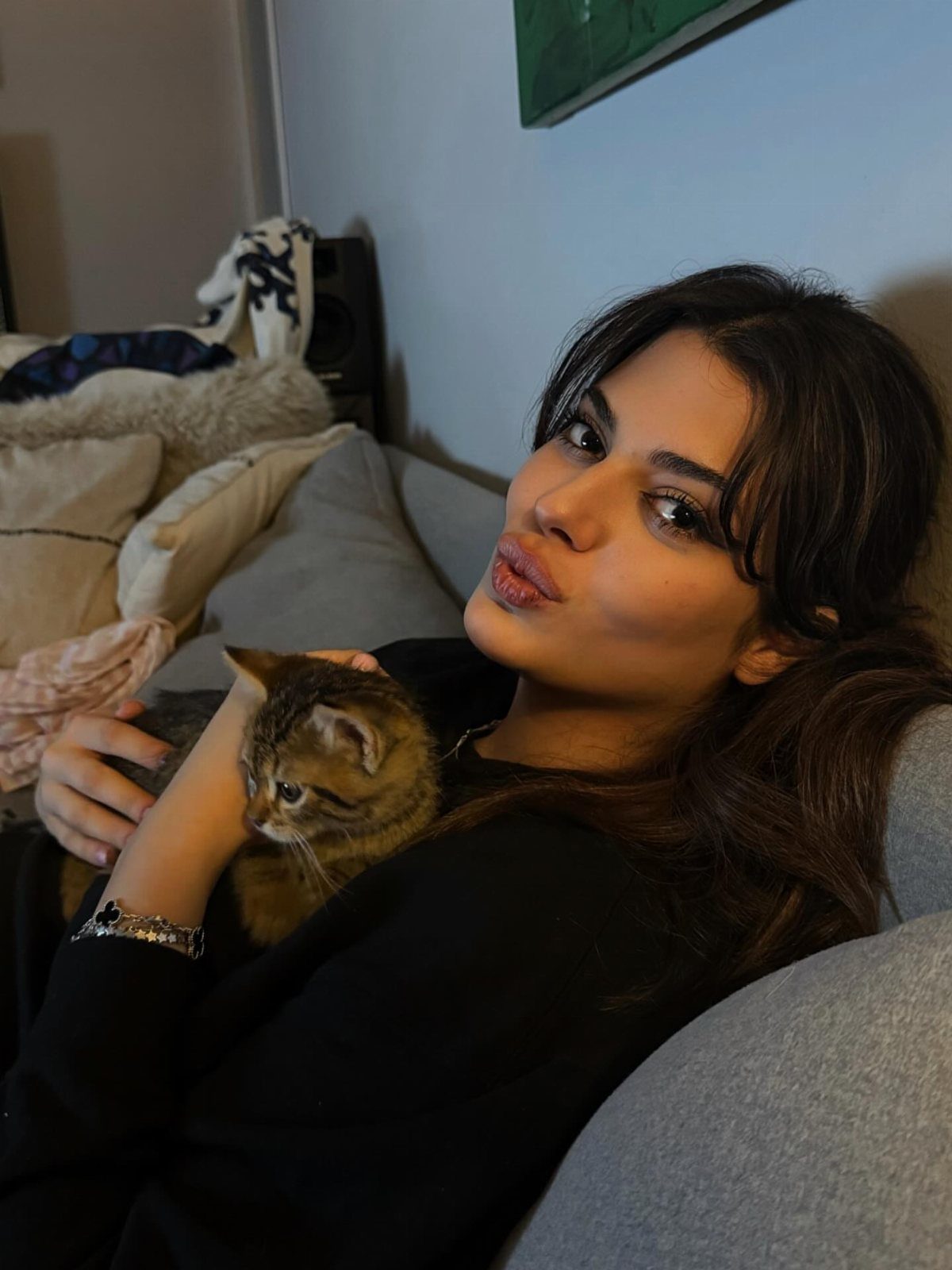 Woman with soft brow-length fringe and relaxed dark waves holding a tabby cat