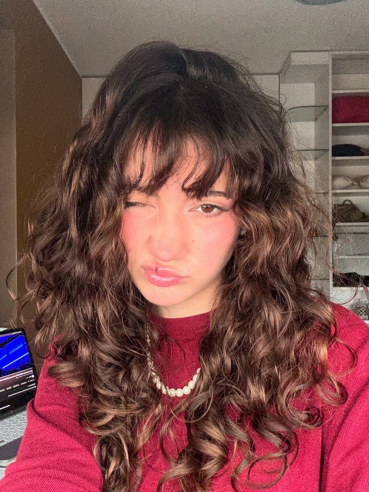 Person showcasing medium-length dark wavy hair with soft full bangs indoors