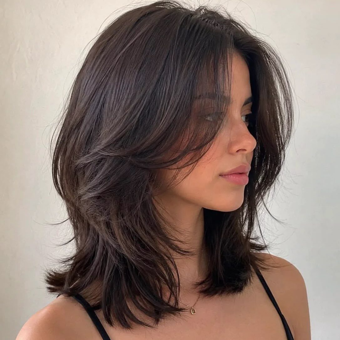 Woman with dark wavy shoulder-length lob and long curtain bangs