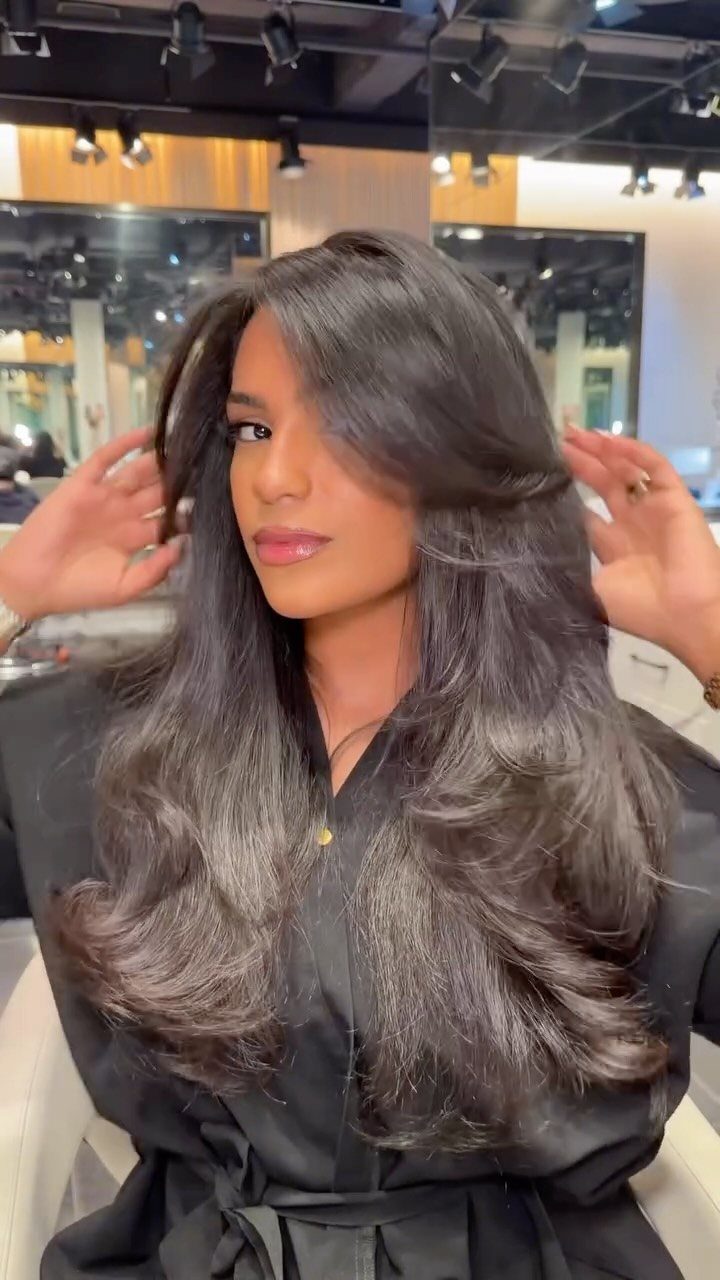 Woman showing long dark hair with soft bangs and layered face-framing curls