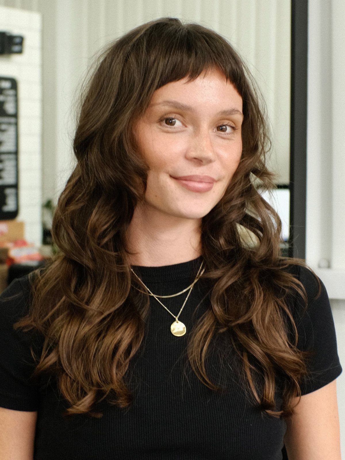 Woman with short micro bangs and long, tousled dark waves