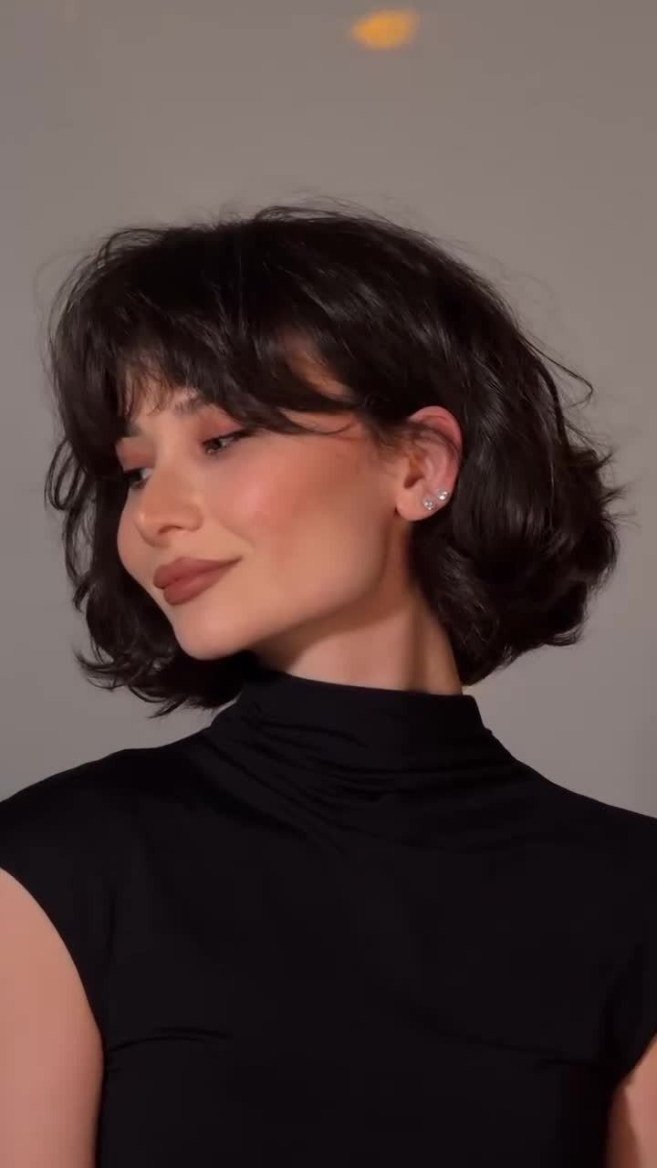 Woman with a short dark wavy bob and softly parted bangs
