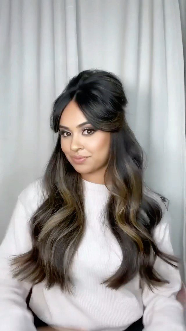 Woman with long wavy hair and full center-parted Bardot bangs