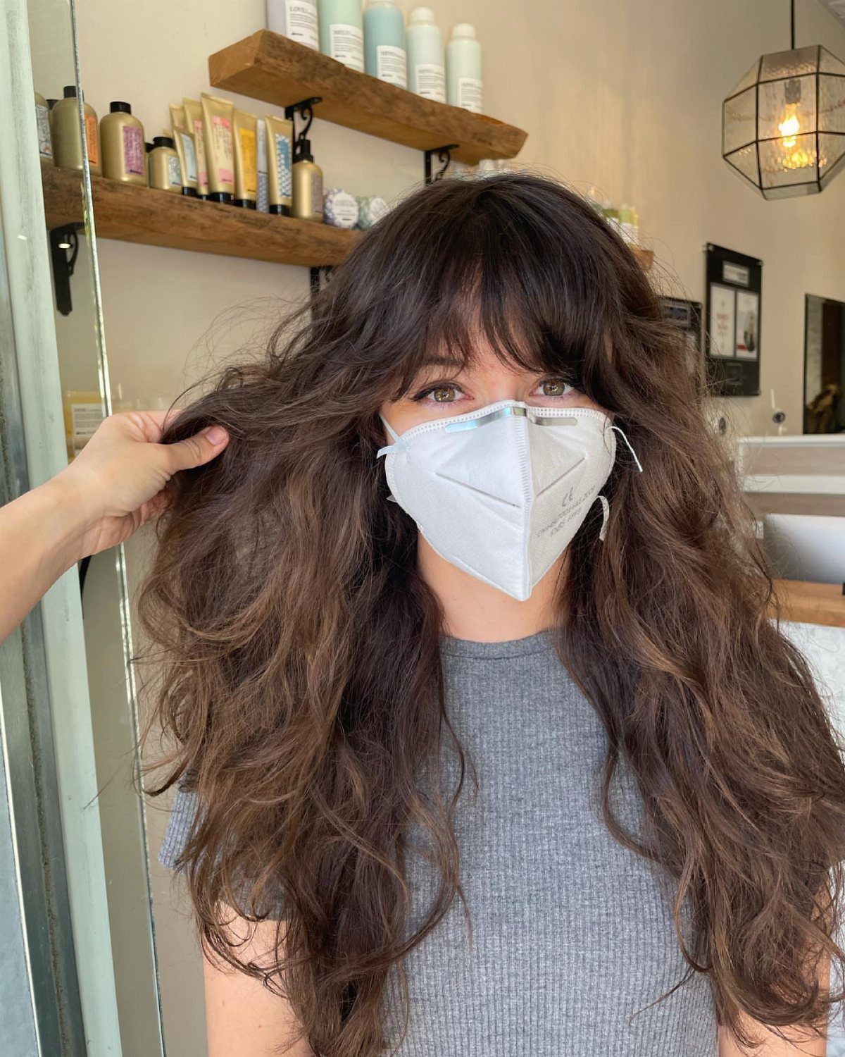 Long dark wavy hair with a rounded fringe in a salon