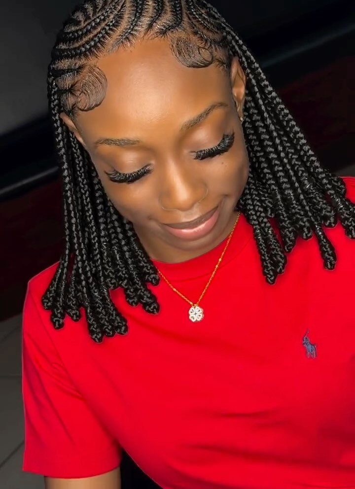 Shoulder-length black box braids frame a woman wearing a red shirt.