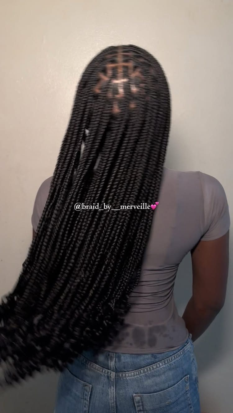 Long black box braids fall down a person's back into loose, wavy ends.