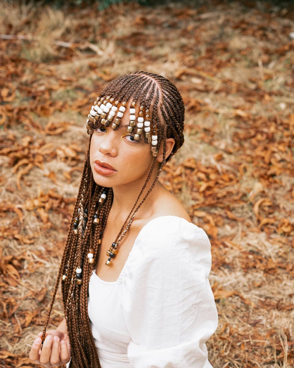 Woman wearing beaded braids arranged across her forehead as bangs