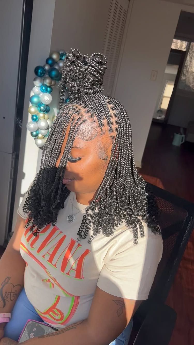 Woman with a high braided bun and loose braids seated indoors
