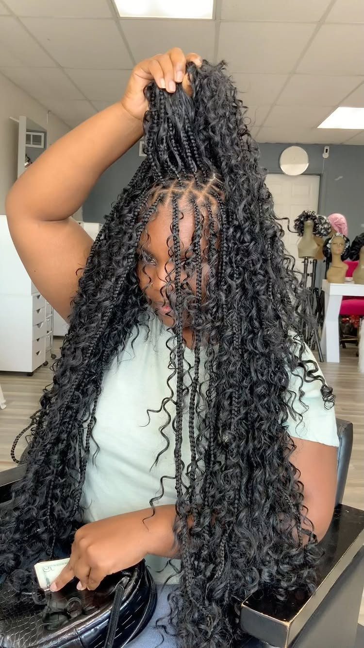 Woman displaying long black braids mixed with loose curly strands in a salon