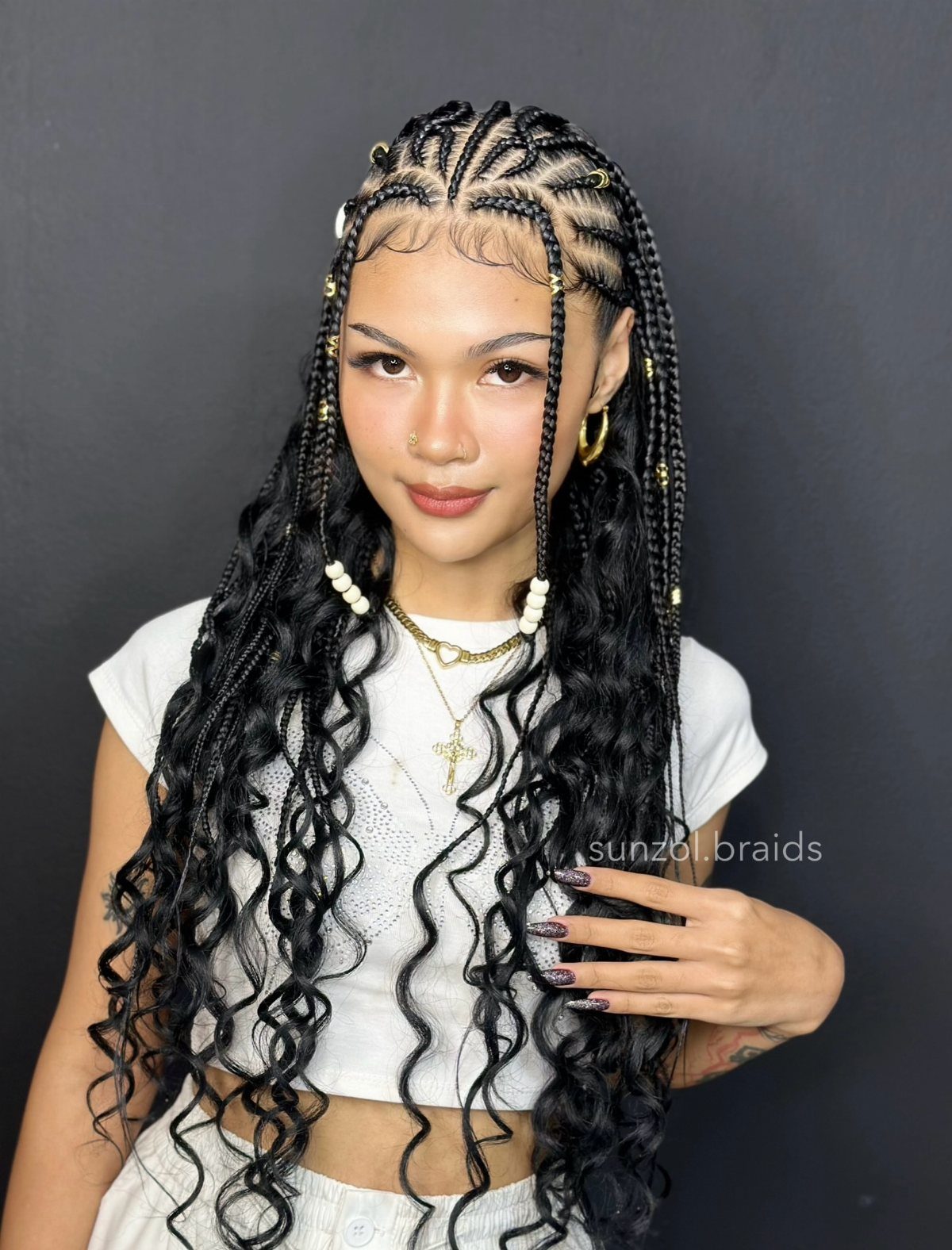 Woman wearing long black braids with the top section pulled back and loose curls hanging