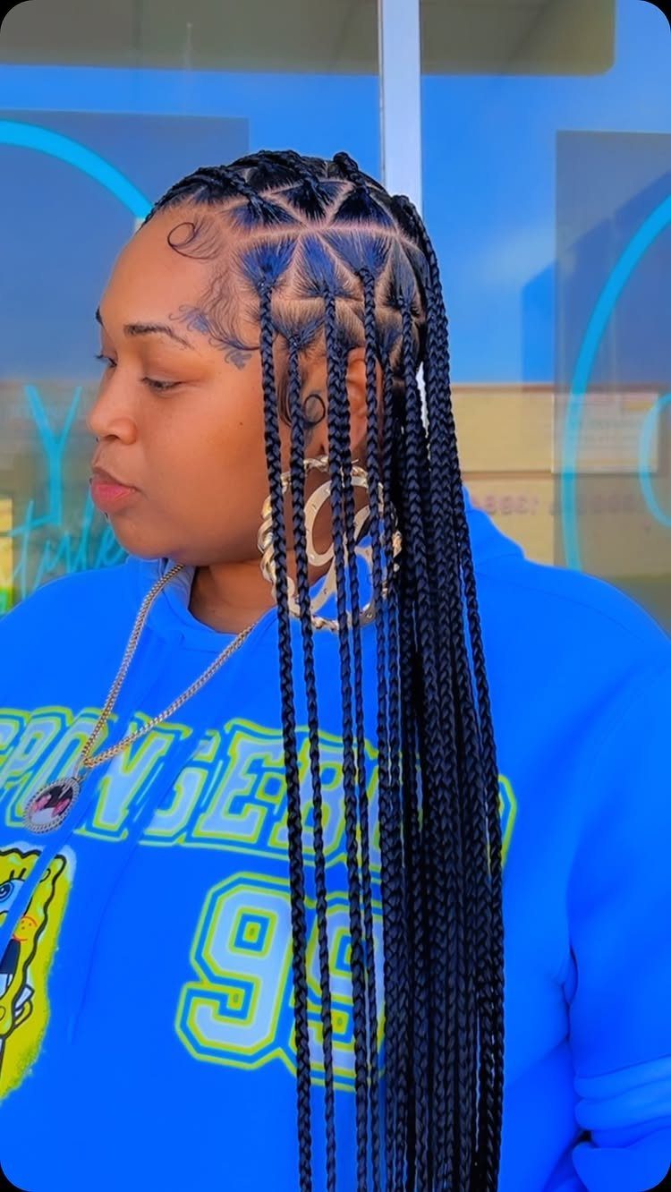 Long black knotless braids hang over a woman’s blue graphic shirt