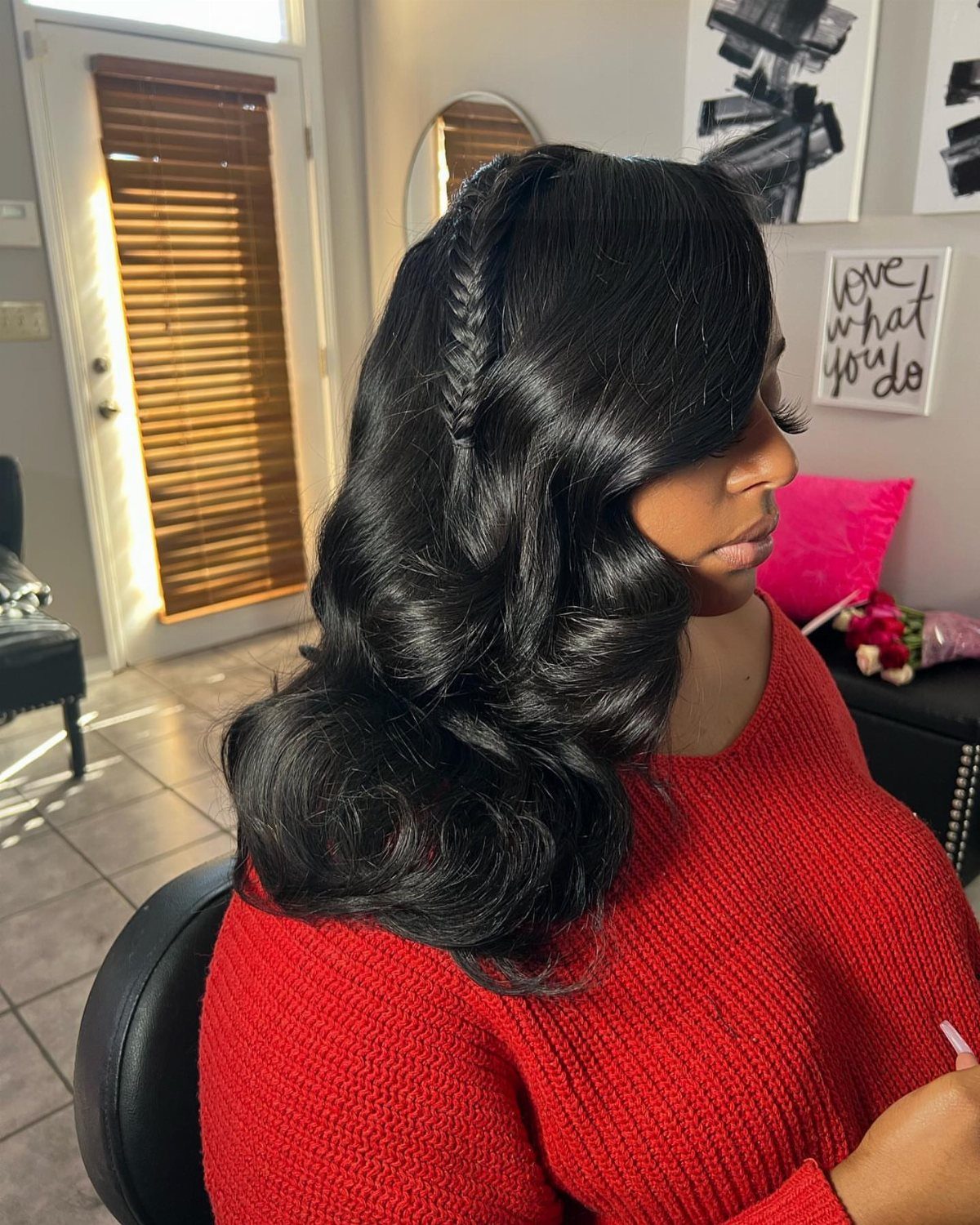 Woman with glossy black waves and a narrow side-swept braid