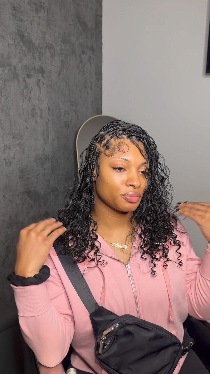 Woman displaying shoulder-length black braids with loose curls and a pink top