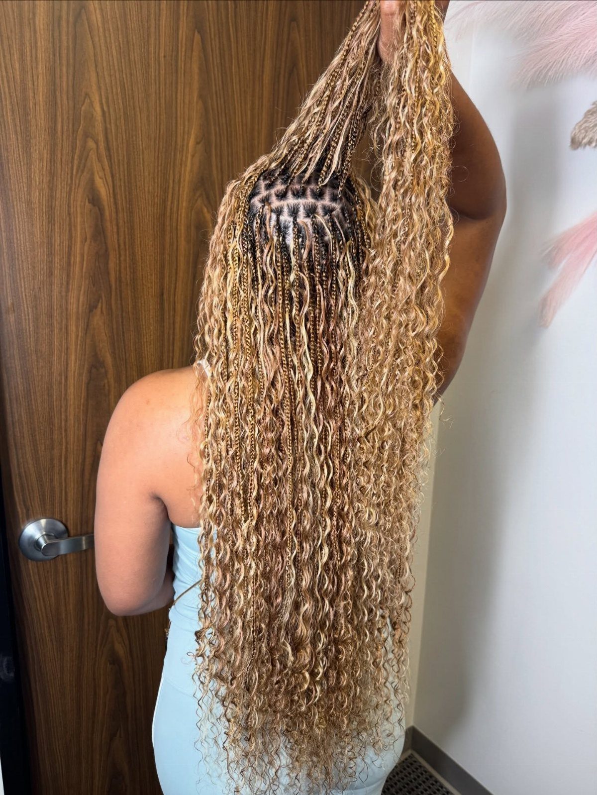 Long blonde boho knotless braids with loose curls shown from behind