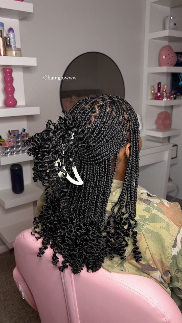 Long dark braids end in loose curls on a seated salon client