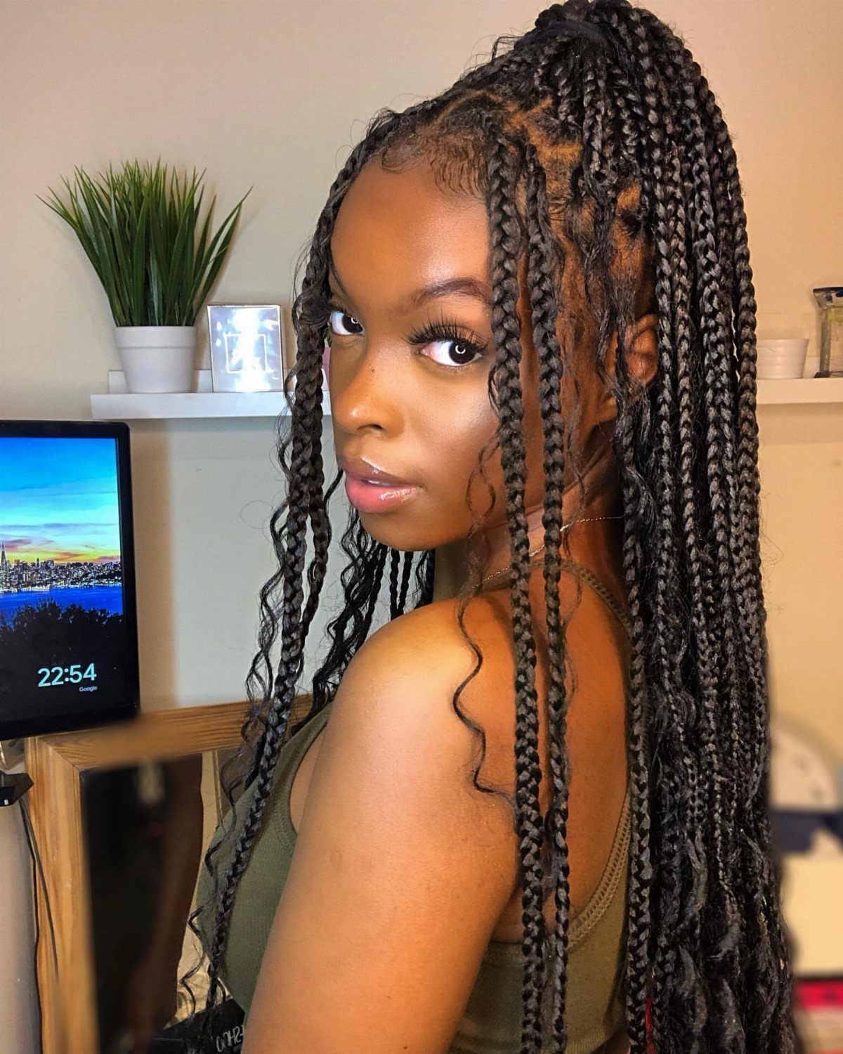 Woman with long black braids in a half-up bun and loose curls