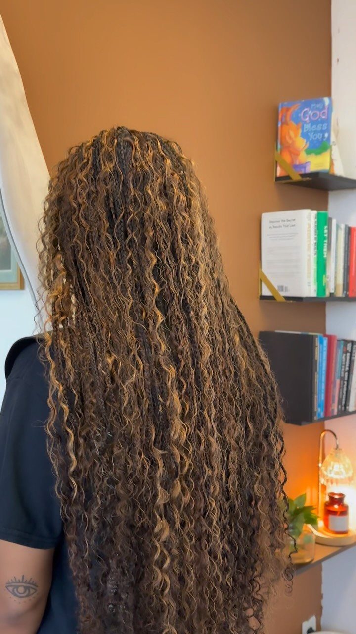 Long boho knotless braids show lighter brown highlights and loose curls