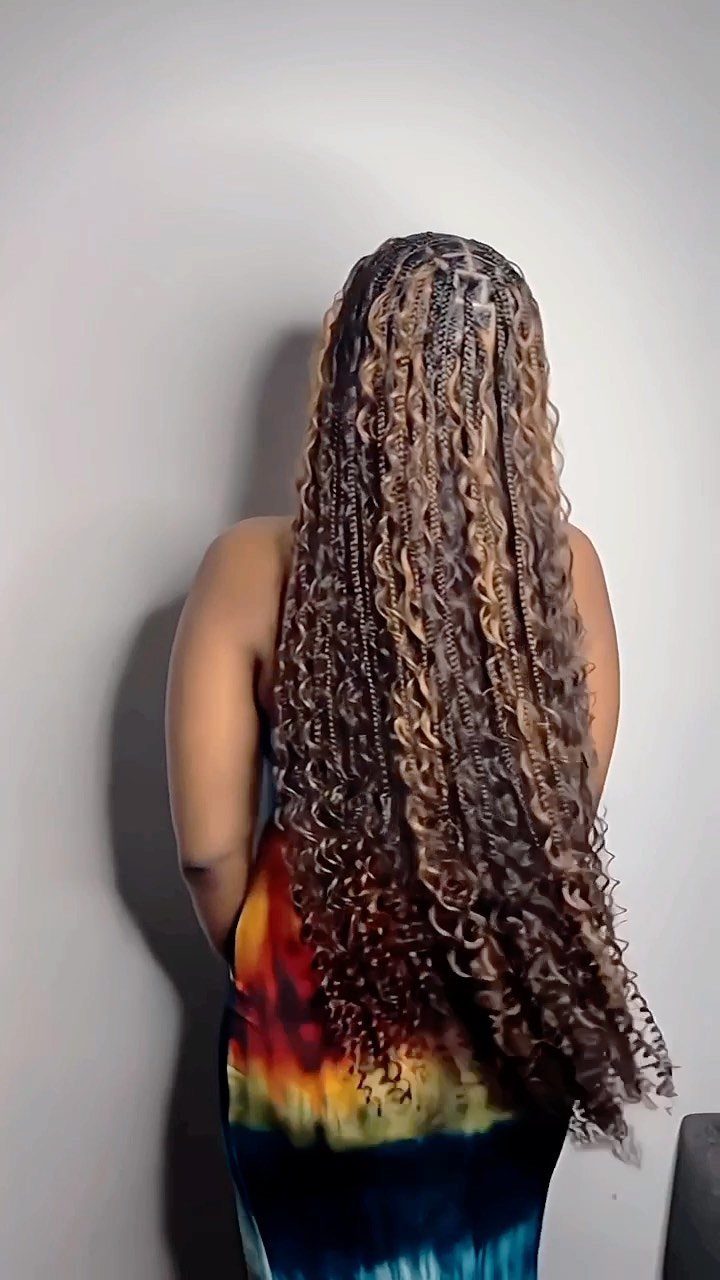 Long brown and blonde boho braids with loose curls fall down a person's back
