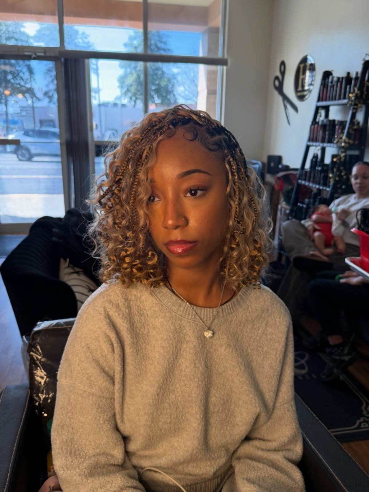 Woman wearing shoulder-length brown boho braids with loose curls in a salon