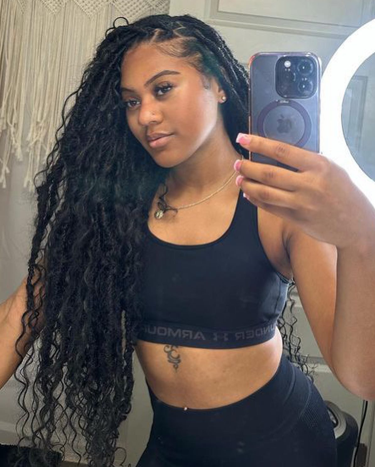 Woman with long side-parted dark boho locs takes a mirror selfie