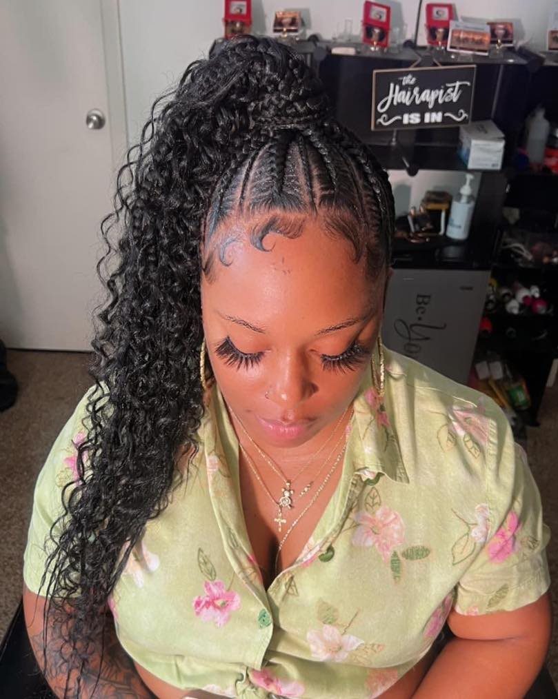 Straight-back cornrows gathered into a long, curly black ponytail
