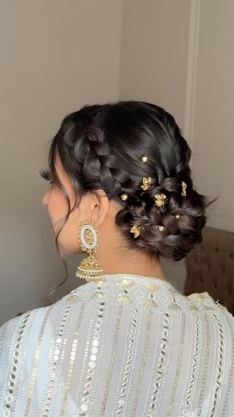 Braided bun decorated with gold floral pins above a pale embroidered garment