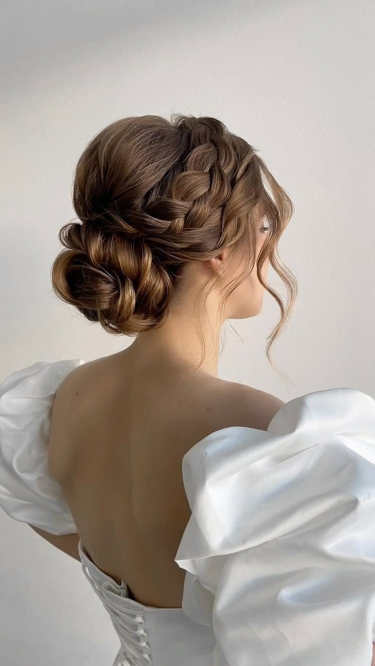 Brown braided bun hairstyle with loose curls on a woman in a white dress