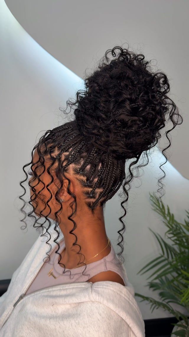 Woman showing thick cornrows gathered into a jumbo curly braided bun