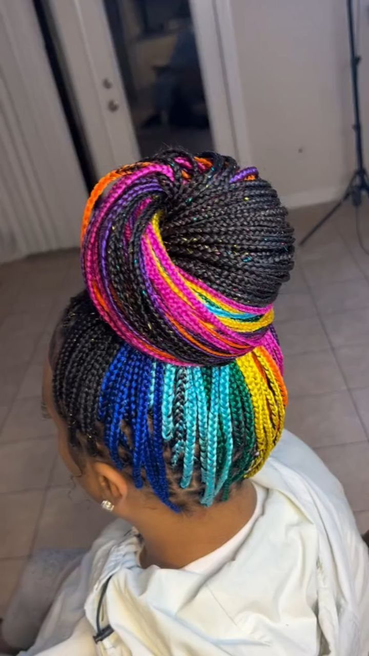 High topknot of thin black braids accented with vivid multicolored extensions