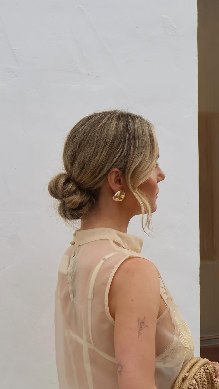Woman showing a low braided bun with loose face-framing tendrils