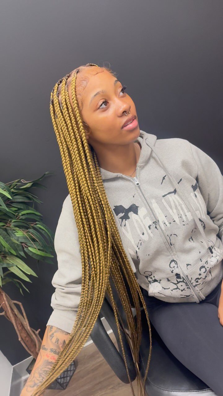 Woman wearing long golden-blonde individual braids with dark roots