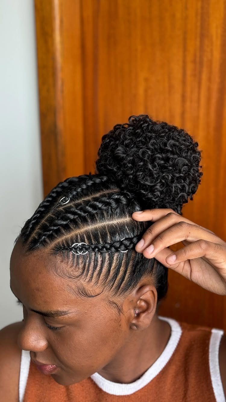 Cornrows gathered into a high curly bun with silver hair cuffs