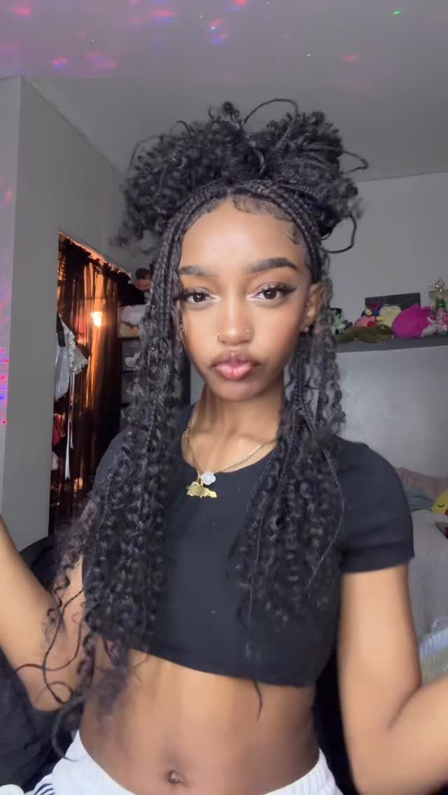 Woman wearing long dark braids styled half-up with curly extensions indoors