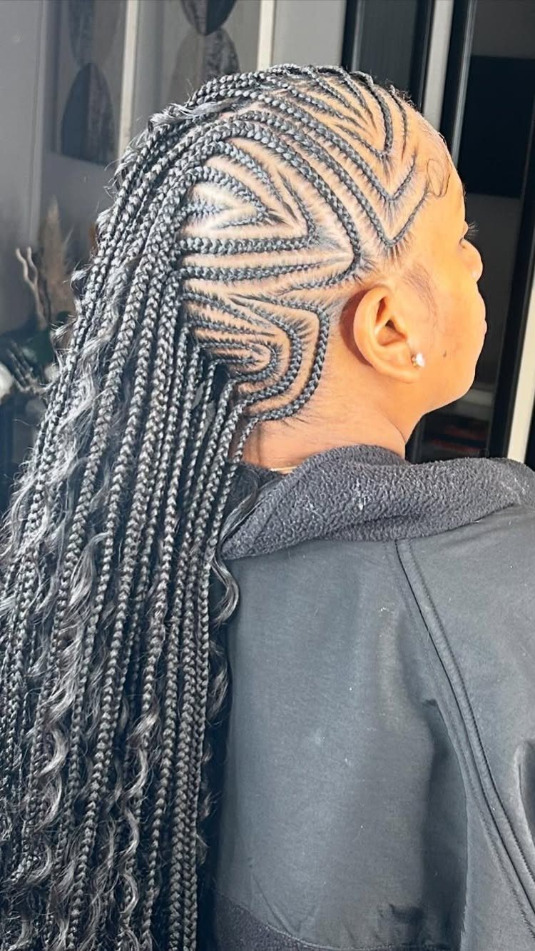Curved cornrows flow into long braids over a dark jacket