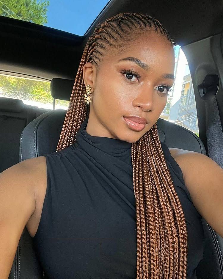 Woman displaying long brown feed-in cornrows in a car