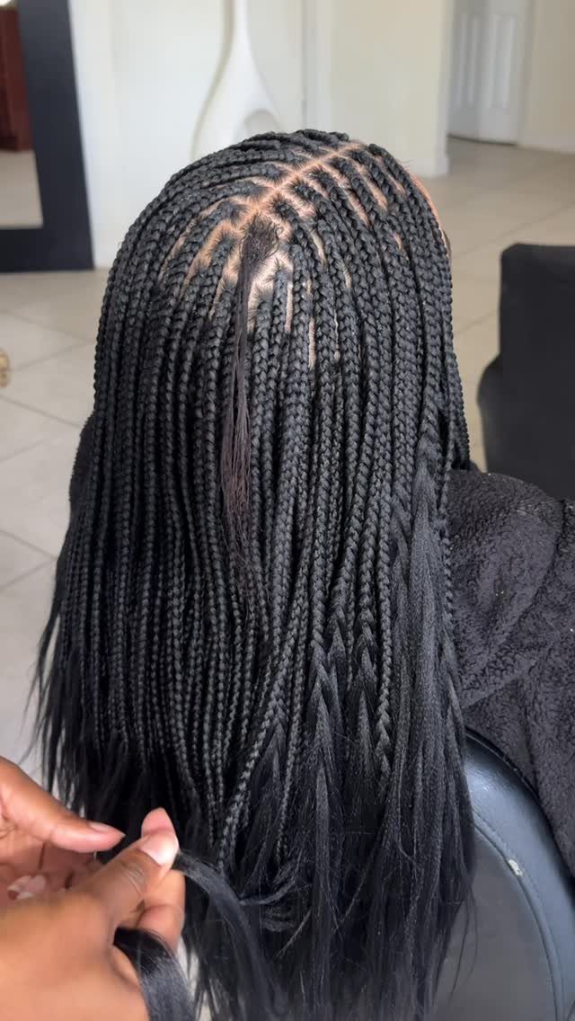 Long black knotless braids shown from the back with natural-looking roots and loose ends