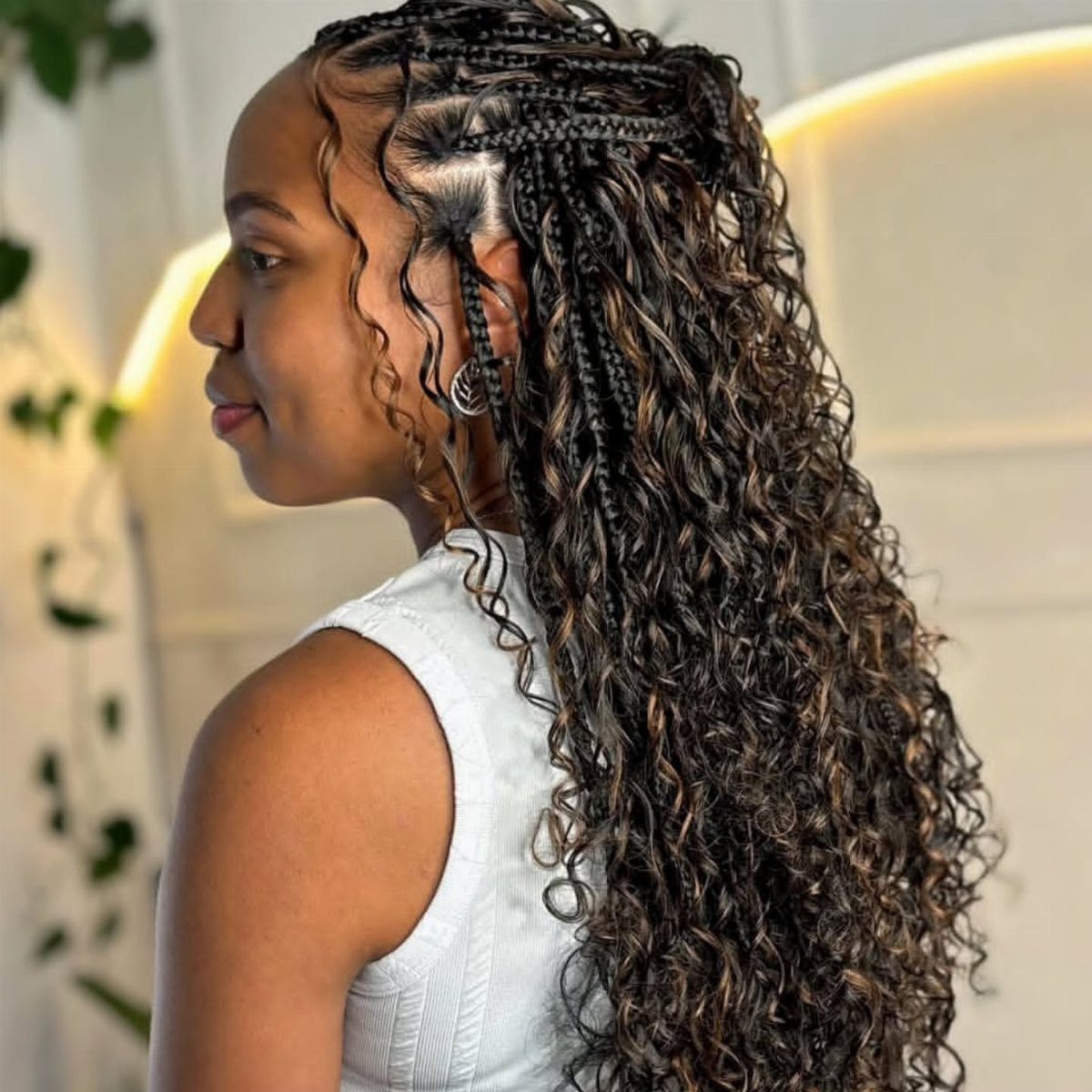 Long curly goddess braids cascade from cornrows down a woman's back
