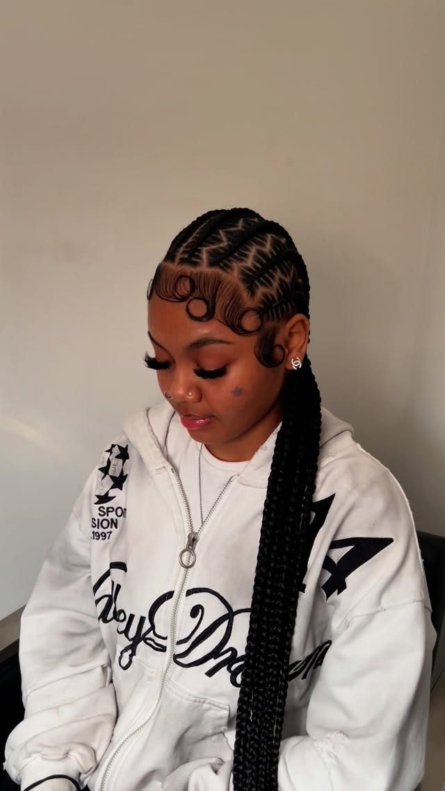Long black stitch braids sweep over one shoulder from neatly patterned cornrows.