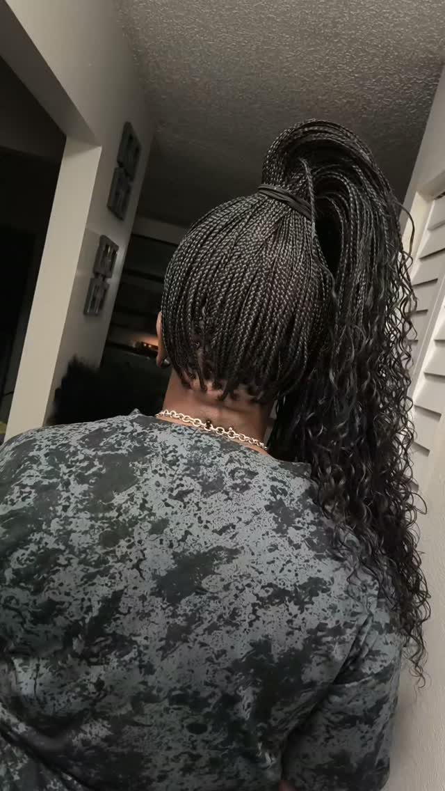 Thin braided ponytail with long curly strands cascading down indoors
