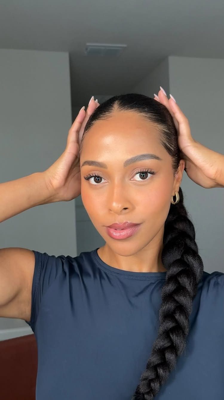 Woman with sleek hair in a long, thick three-strand braid over one shoulder