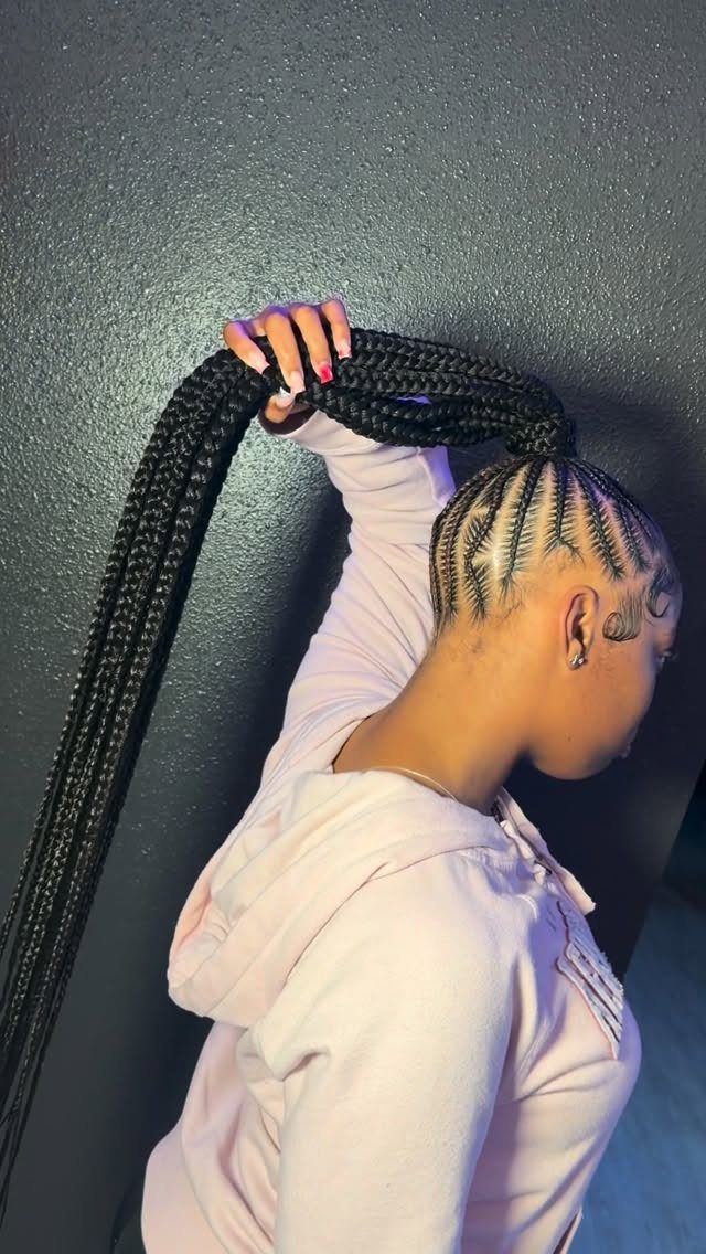 Feed-in braids gathered into a long ponytail held above a pale pink hoodie