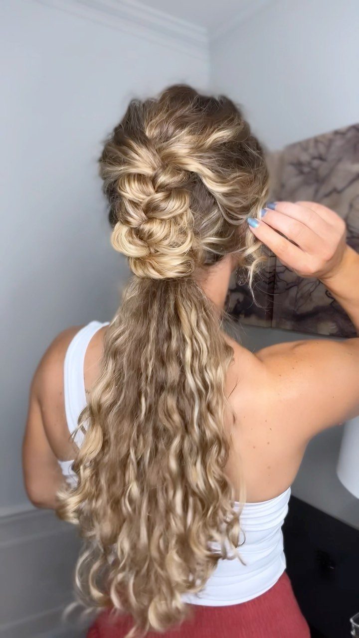 Raised French braid gathered into a long, curly blonde ponytail
