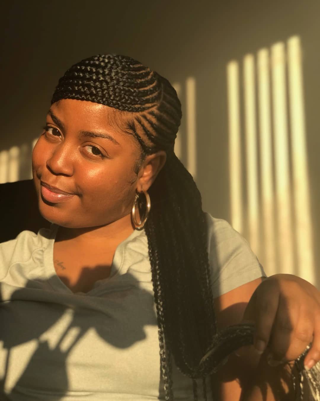 Woman wearing a sleek side-swept braided ponytail in warm indoor sunlight