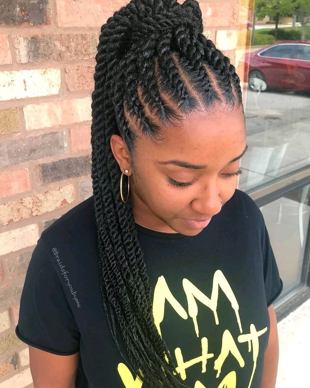High ponytail of long black twists gathered over a woman's shoulder